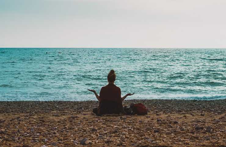 Donna che medita sulla spiaggia