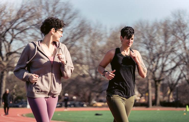 Due donne che corrono su una pista di atletica in un parco