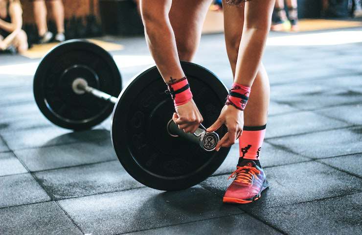 Donna che sistema un bilanciere con dei pesi in palestra