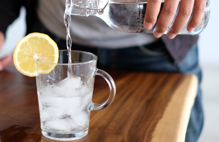 Uomo che versa acqua in un bicchiere