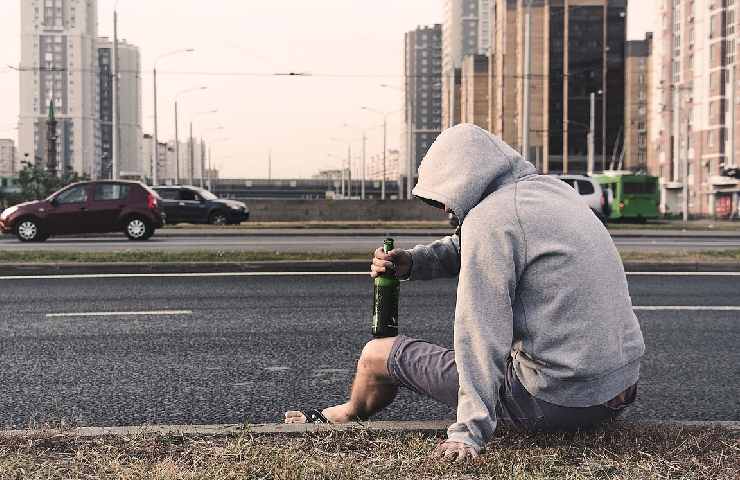 Uomo disperato che beve a bordo della strada