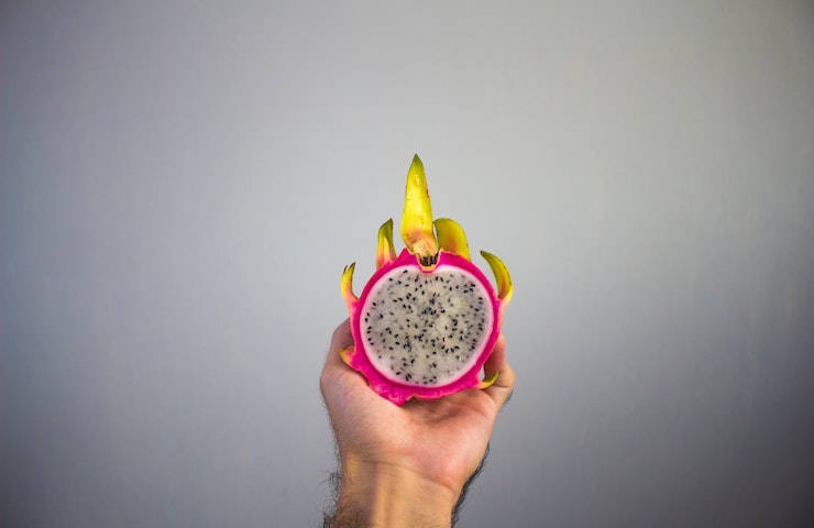 Dragon Fruit tagliato a metà e tenuto in bella mostra in una mano