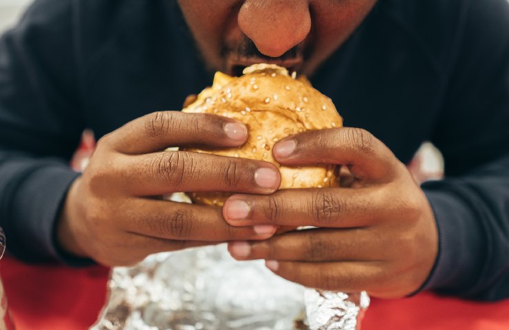 Uomo che mangia un hamburger