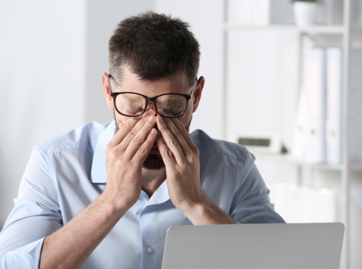 Un uomo si sfrega gli occhi davanti al pc