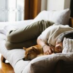 Una donna che dorme sul divano con il suo cane