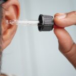 Un uomo intento a mettere delle gocce nelle orecchie