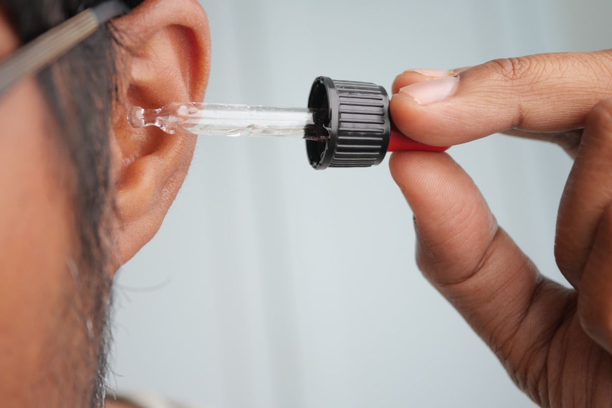 Un uomo intento a mettere delle gocce nelle orecchie